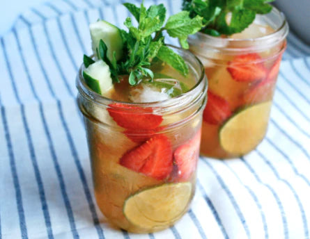 Pimm’s Cup cocktail with strawberries cucumber and mint served in mason jars representing refreshing New Orleans summer drink