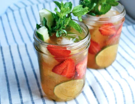 Pimm’s Cup cocktail with strawberries cucumber and mint served in mason jars representing refreshing New Orleans summer drink