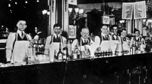 bartenders preparing Ramos Gin Fizz at historic New Orleans bar with multiple shakers and classic cocktail setup