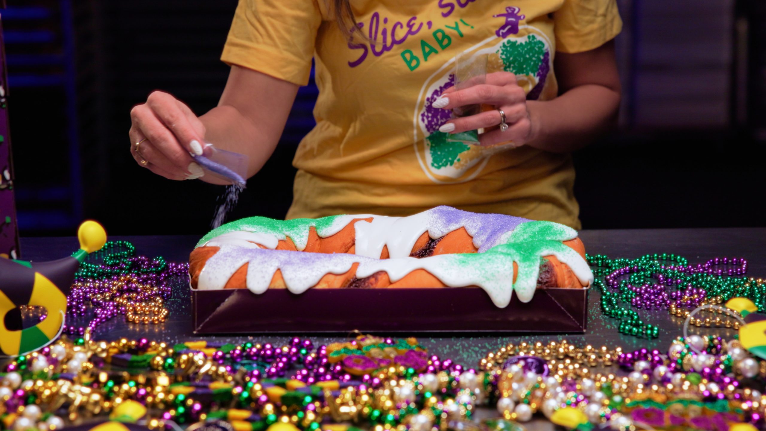 A Gambino's king cake iced in purple, green, and gold, photographed whole before slicing
