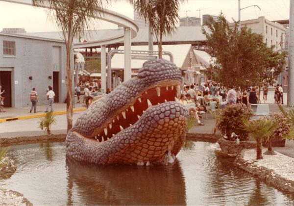 large alligator sculpture at 1984 New Orleans World’s Fair with visitors gathered around water feature and exhibition area.