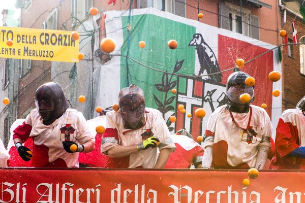 Participants in protective gear throwing oranges during Ivrea Carnival Battle of the Oranges festival in Italy, a historic pre-Lenten tradition.