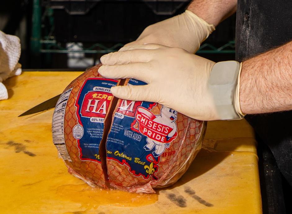 A Chisesi ham is being sliced at Mahony’s Poboys to make their signature root beer-glazed ham and cheese poboy.