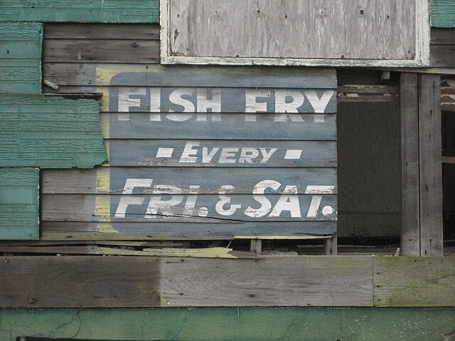 Weathered old sign on side of building Uptown, advertising "Fish Fry" held every Friday and Saturday. Photo from March 2007 during Lent.