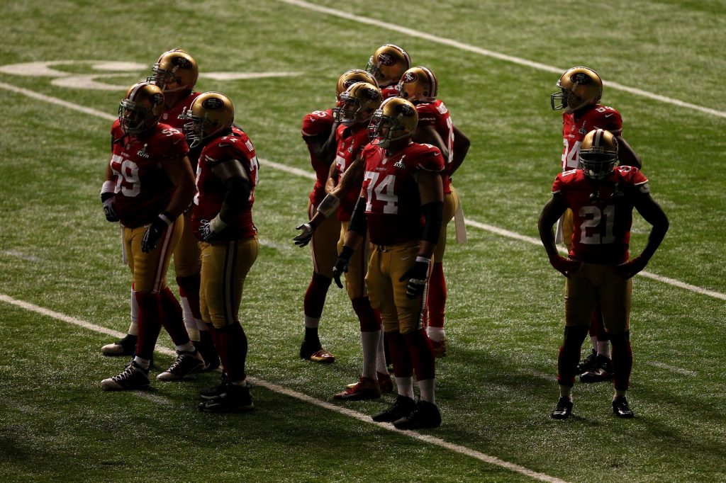 The San Francisco 49ers stand in partial darkness on the field during Super Bowl XLVII in 2013 while the Superdome experienced a power outage.